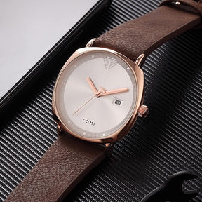 TOMI ORIGINAL MONTRE UNISEX ACIER INOXYDABLE DORÉ CEINTURE MARRON EN CUIR FOND BLANC